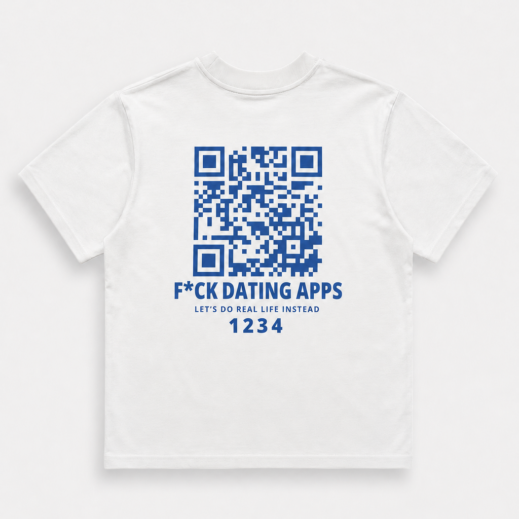 A white short-sleeve t-shirt with a blue graphic print on the front, featuring a QR code, the text 'F*CK DATING APPS', 'LET'S DO REAL LIFE INSTEAD', and a unique code